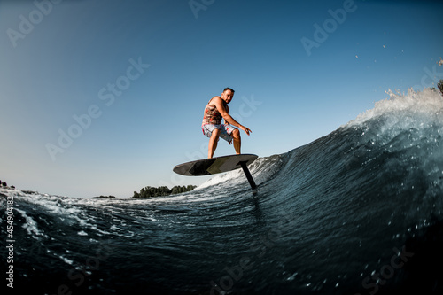 healthy man riding on the wave with hydrofoil foilboard on background of blue sky