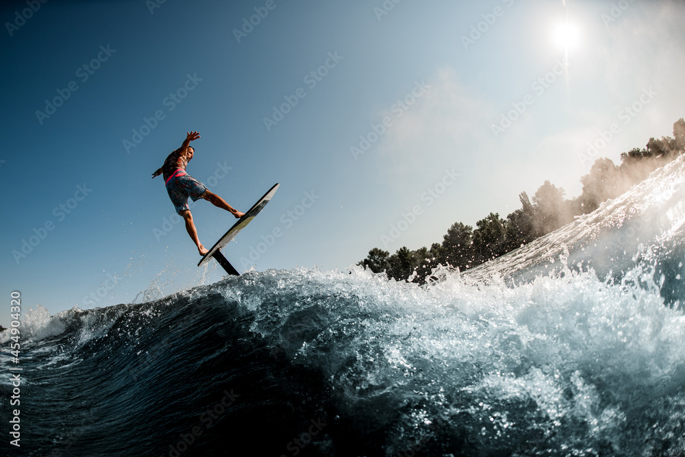 Active guy having fun and rides the wave with hydrofoil foilboard