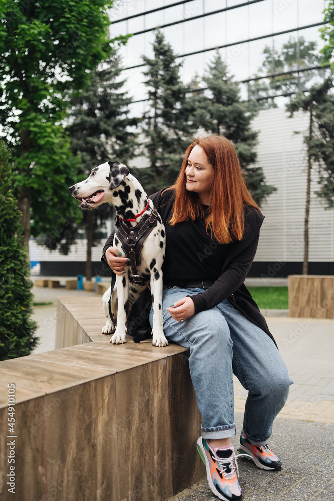 Happy woman posing and playing with her dalmatian dog during a urban city walk. Friendship, love and care concept Happy woman posing and playing with her dalmatian dog during a urban city walk. Friendship, love and care concept