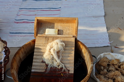 A wooden washboard, a bar of soap and sheep's wool in a wooden basin of water. hand washing clothing.