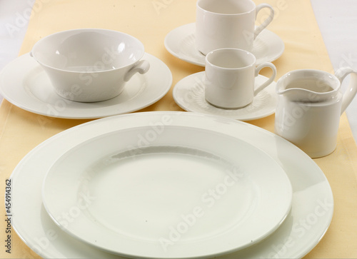 Vajilla de porcelana blanca sobre mantel Amarillo. White porcelain tableware on a yellow tablecloth.