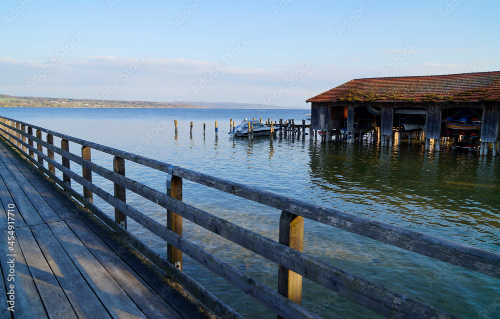 a scenic view from a wooden pier of lake Ammersee and  a boat house (Schondorf in Germany)
