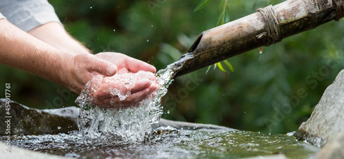 Mountain spring. A man washes his hands in a bowl with fresh, natural, cold drinking water. Ecology of the planet. Close-up. Japanese style.