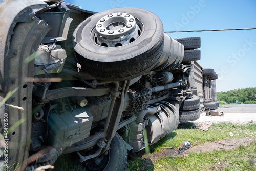The truck is lying on its side in a car accident on the highway
