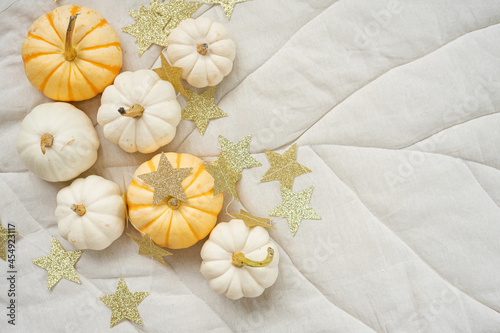 Sweet mini pumpkins and stars garland on a beige leaf blanket with copy space. Thanksgiving decoration.