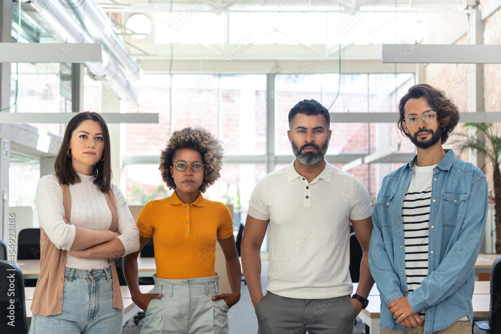 Multiracial group of coworkers looking at camera. Young entrepreneurs in coworking space. Multiracial group of coworkers looking at camera. Young entrepreneurs in coworking space.