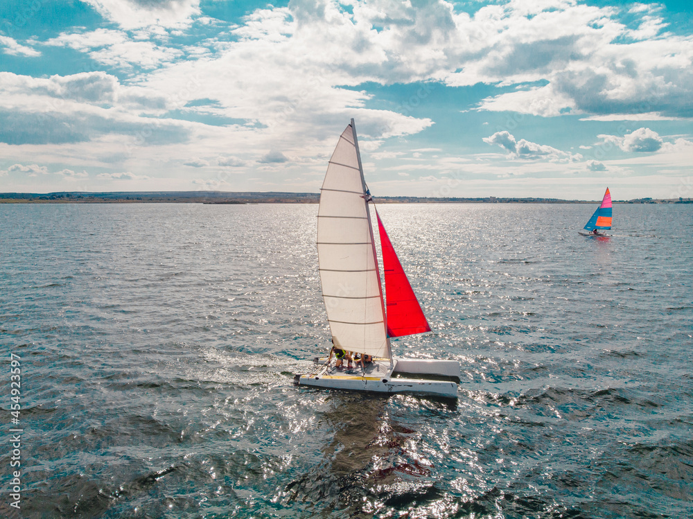 Fototapeta premium Drone photo of beautiful catamaran yacht going upwind on a lake under a sunny sky