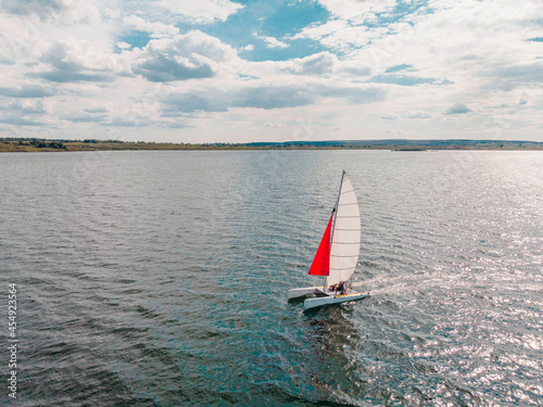 Drone photo of beautiful catamaran yacht going upwind on a lake under a sunny sky