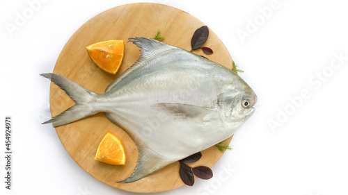 Top view of Silver Pomfret,White Pomfret fish dish cooking with various ingredients. Fresh raw fish decorated on a wooden pad, white background.Selective focus. photo