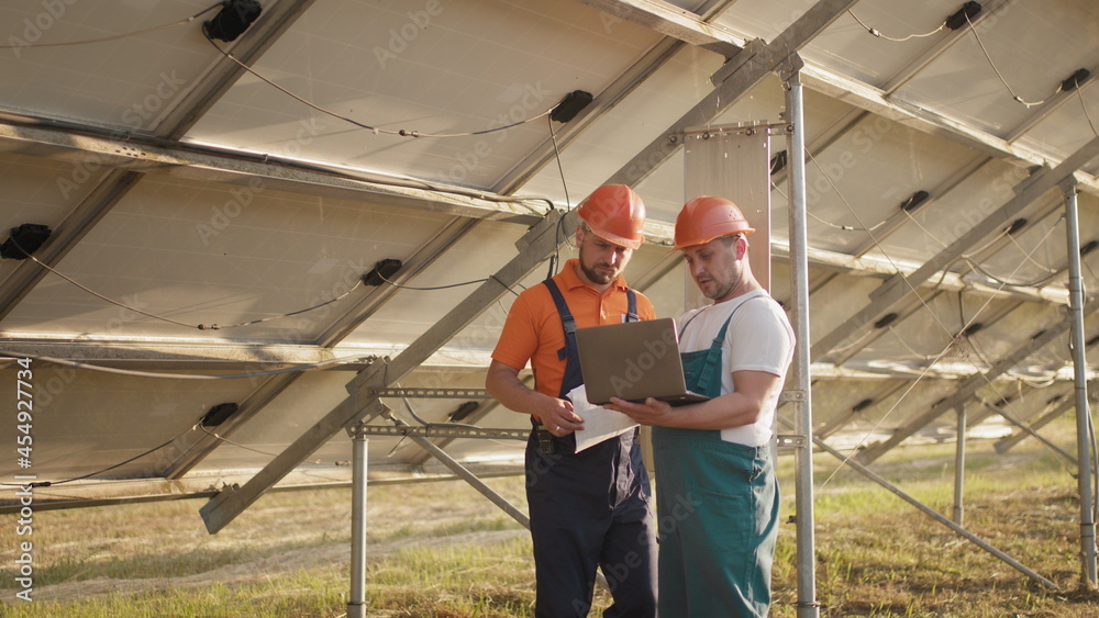 Technicians with tablet checking the panels at solar energy installation. Technician of energy checking the solar cell panels at solar farm energy. Smart engineer installation solar cell Technicians with tablet checking the panels at solar energy installation. Technician of energy checking the solar cell panels at solar farm energy. Smart engineer installation solar cell