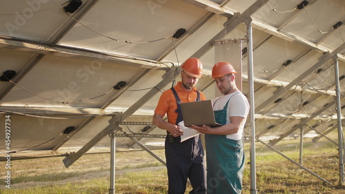 Technicians with tablet checking the panels at solar energy installation. Technician of energy checking the solar cell panels at solar farm energy. Smart engineer installation solar cell