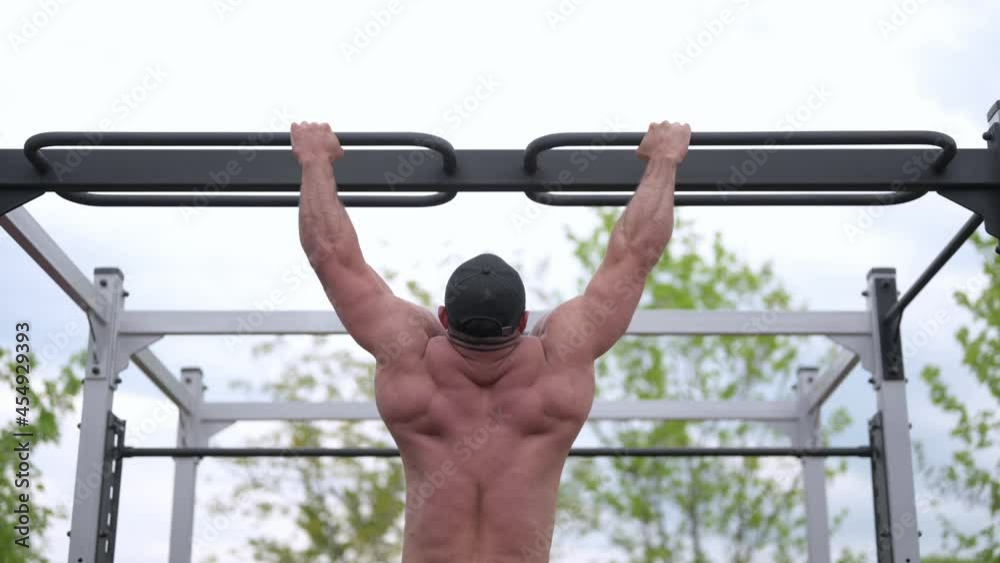 strong male athlete doing pull ups on crossbar outdoors workout training sport activity