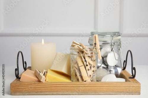 Wooden tray with many clothespins, candles and soap bars on white table