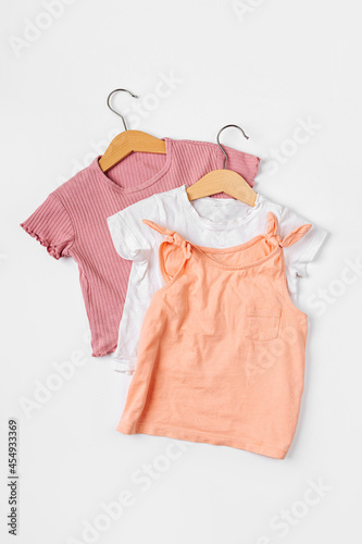 T-shirts on hanger. Set of baby clothes and accessories for spring, autumn or summer on white background. Fashion kids outfit. Flat lay, top view