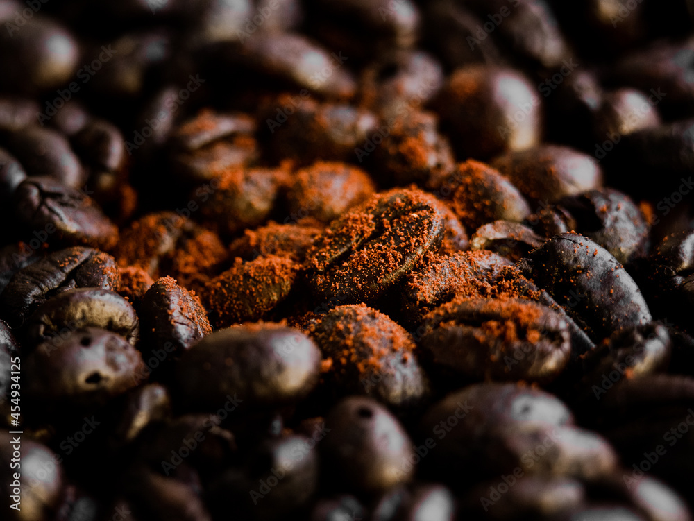 Ground coffee falling on roasted coffee beans background. Organic coffee seeds. Ground coffee falling on roasted coffee beans background. Organic coffee seeds.