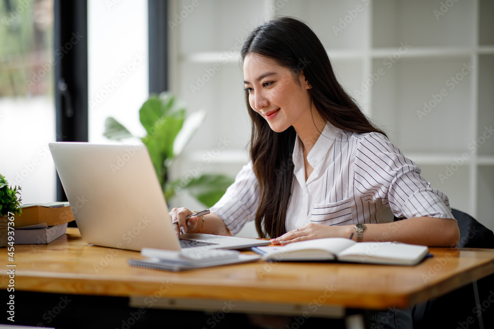 Portrait of asian young woman using laptop at cafe, she is working on laptop computer at a coffee shop.