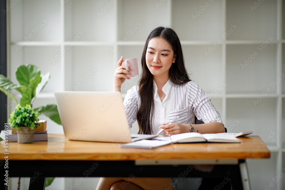 Portrait of asian young woman using laptop at cafe, she is working on laptop computer at a coffee shop.