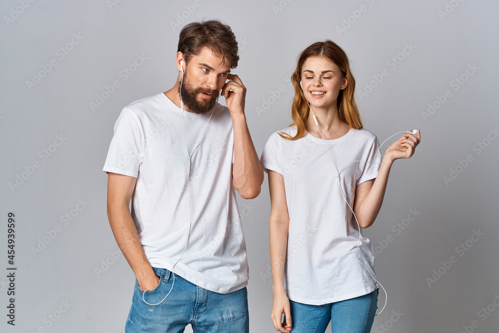 cheerful young couple in white t-shirts with headphones listening to music joy friendship cheerful young couple in white t-shirts with headphones listening to music joy friendship