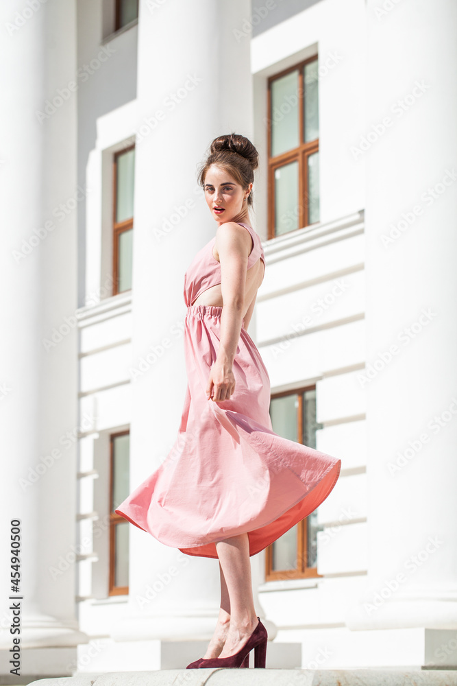 Young woman in a luxurious beige dress posing on the street