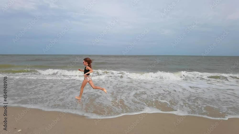 Little kid girl plays on beach shallow water line summer rest during vacations Little kid girl plays on beach shallow water line summer rest during vacations