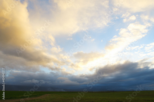 Dramatic skyline background of colored cloud against a distant field and horizon