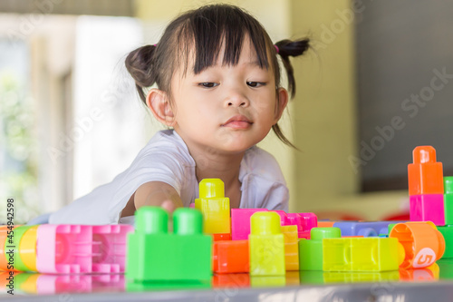 Happy Asian child girl playing the plastic block toys. Learning and education concept. Smiling little baby.