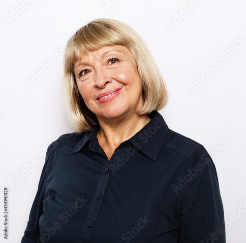 Photo of gorgeous mature old woman standing isolated over white background wall looking camera