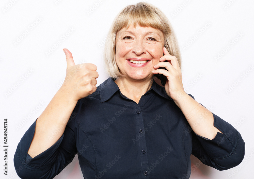 Photo of crazy ecstatic old woman use smartphone impressed social media like feedback win raise fists scream yes isolated over white background Photo of crazy ecstatic old woman use smartphone impressed social media like feedback win raise fists scream yes isolated over white background