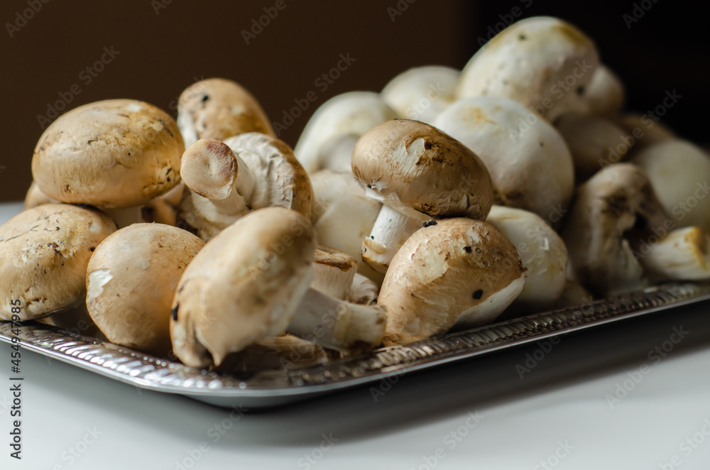 Portobello and white mushrooms on a silver plate, vegetables from an organic farm Portobello and white mushrooms on a silver plate, vegetables from an organic farm