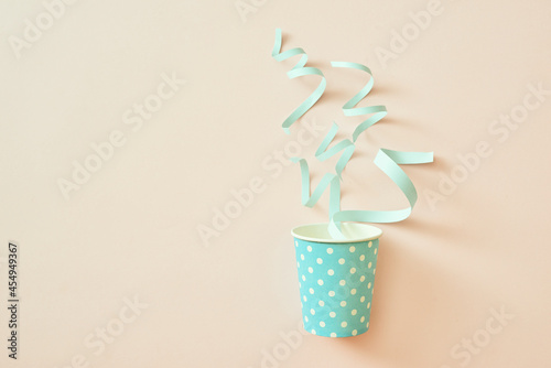 Fototapeta Naklejka Na Ścianę i Meble -  Celebration concept. Paper cup with confetti on a beige background.