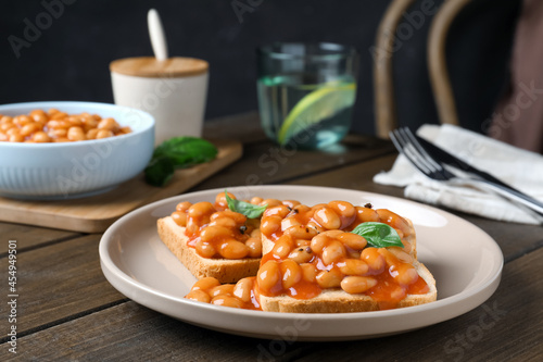 Toasts with delicious canned beans on wooden table