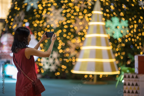 Asian female using smartphone for taking a photo of Christmas festival in town.
