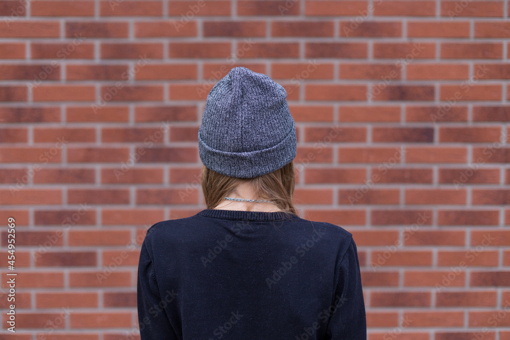 a person standing near a brick wall, anonymous 