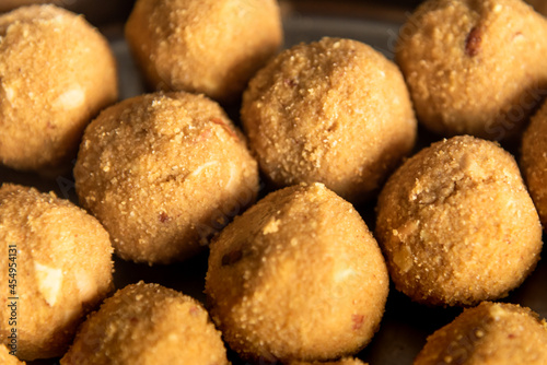 Closeup selective focus of homemade besan Laddoo or roasted gram flour mixed with desi Ghee and sugar or jaggery to make it round shape sweet and tasty.