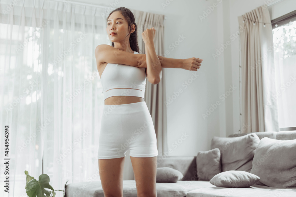 Woman stretching arms after exercise at home. Young asian healthy woman in sportwear workout at home. Home exercise. Woman stretching arms after exercise at home. Young asian healthy woman in sportwear workout at home. Home exercise.