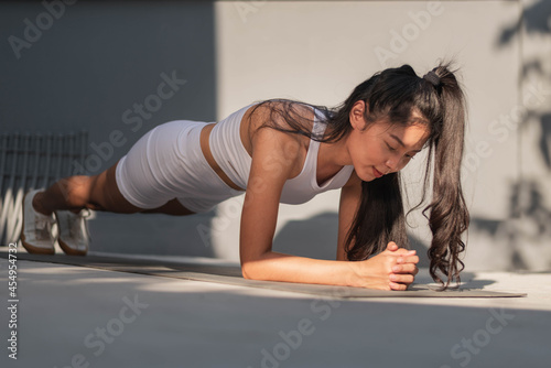 Young woman exercising at home. Asian healthy woman in sportwear doing plank exercise at home. Home exercise. photo