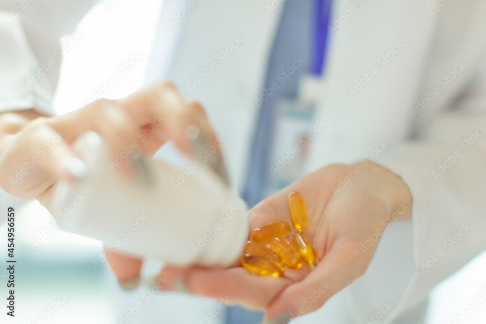 Young asian woman doctor looking at camera.Smiling female pharmacist holding a pill, health care and prevention concept, hand close up. Young asian woman doctor looking at camera.Smiling female pharmacist holding a pill, health care and prevention concept, hand close up.