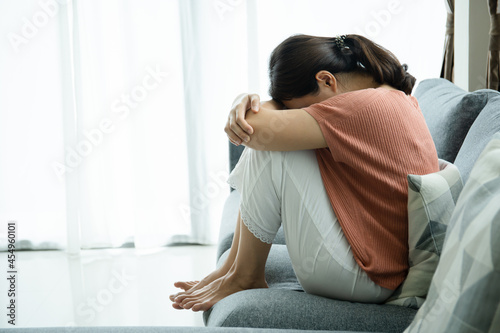 Unhappy Asian young woman having a depressed disorder problem and living alone in living room.