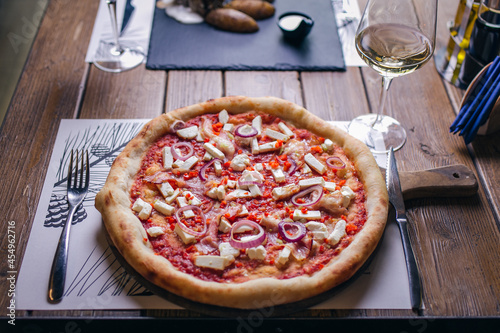 Pizza with bacon, onion and cheese at restaurant table