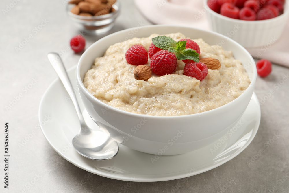 Tasty oatmeal porridge with raspberries and almond nuts served on light table