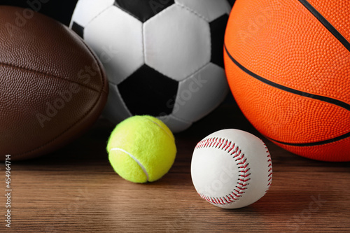 Set of different sport balls on wooden surface, closeup