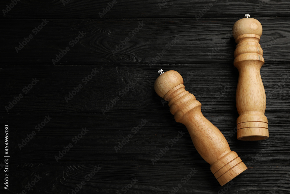 Salt and pepper shakers on black wooden table, flat lay. Space for text Salt and pepper shakers on black wooden table, flat lay. Space for text