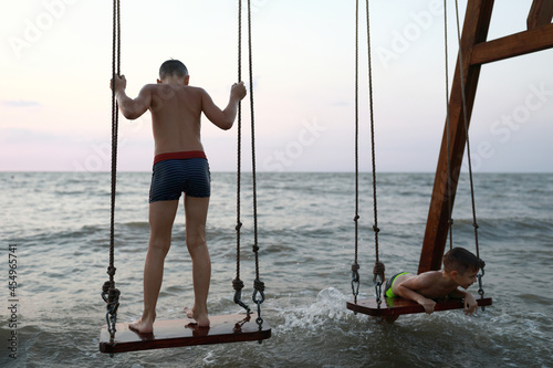 Two children swinging on swing in Sea of Azov