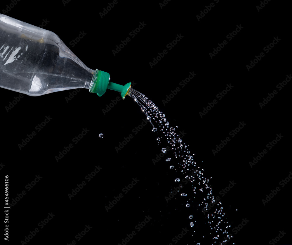 Watering can form water bottle in action on black background Watering can form water bottle in action on black background