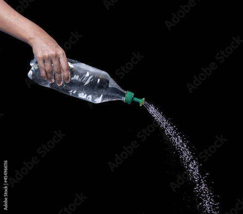 Watering can form water bottle in action on black background