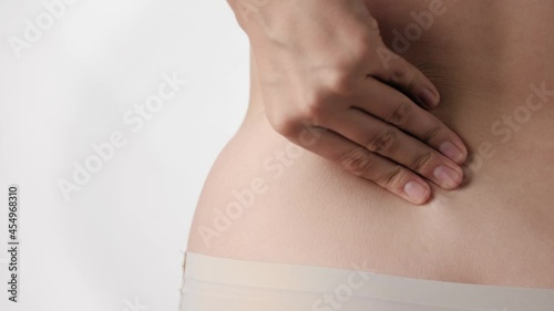 Wallpaper Mural Backache. Female hand touches and presses on lower back on white background. Close-up and slow motion Torontodigital.ca