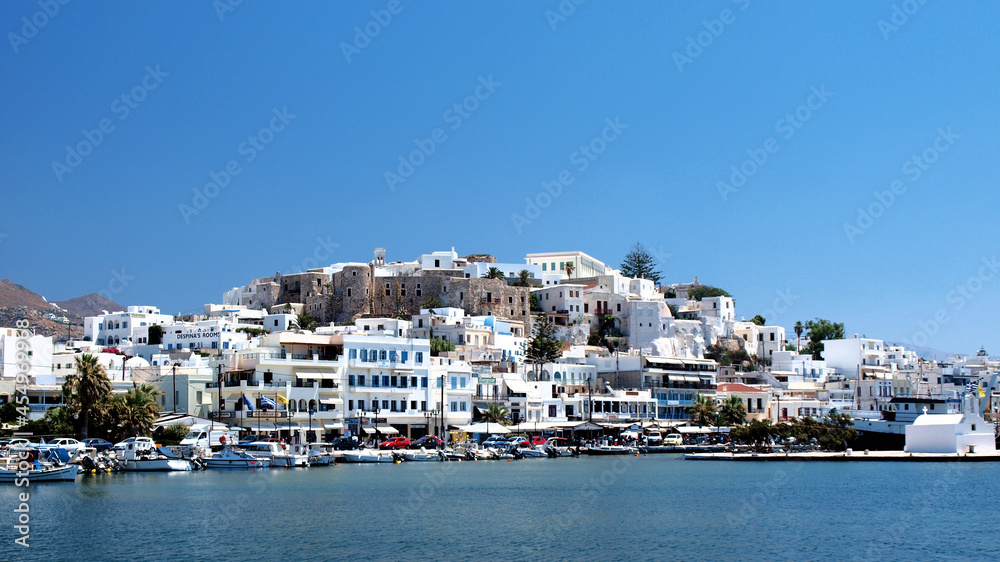 Port on isle of Naxos with traditional white houses with bluew windows, Greece