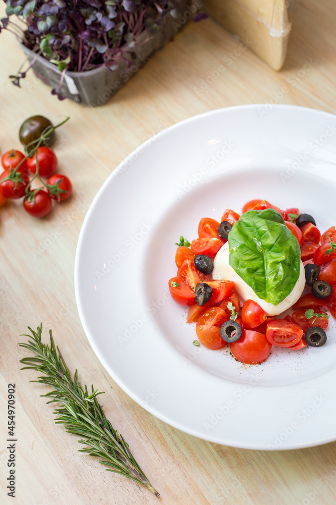 Plate with fresh salad with tomatoes, basil leaves and mozzarella Plate with fresh salad with tomatoes, basil leaves and mozzarella