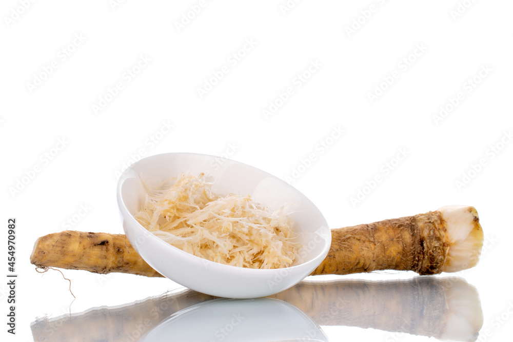 One whole spicy horseradish root and grated horseradish in a white saucer, close-up isolated on white. One whole spicy horseradish root and grated horseradish in a white saucer, close-up isolated on white.