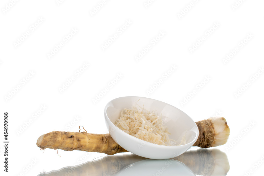 One whole spicy horseradish root and grated horseradish in a white saucer, close-up isolated on white. One whole spicy horseradish root and grated horseradish in a white saucer, close-up isolated on white.